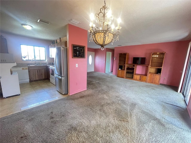 kitchen featuring a notable chandelier, white appliances, hanging light fixtures, a textured ceiling, and light carpet