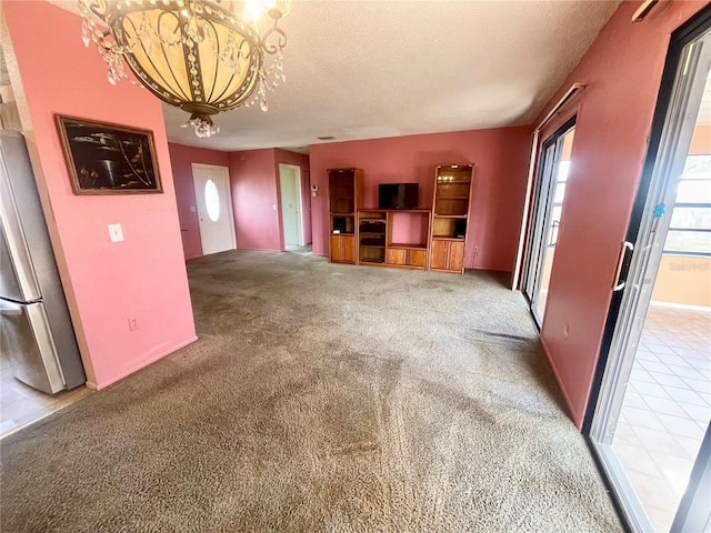 unfurnished living room with carpet, a chandelier, and a textured ceiling