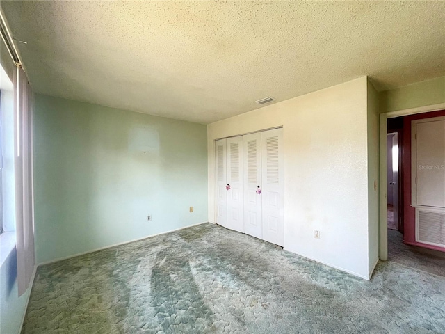 unfurnished bedroom featuring a textured ceiling, a closet, and carpet flooring