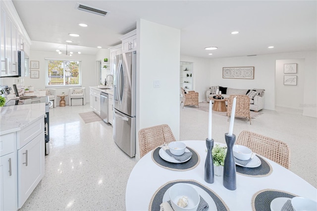 kitchen featuring sink, light stone counters, stainless steel appliances, and white cabinetry