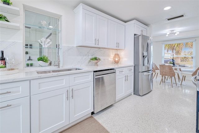 kitchen with white cabinets, backsplash, appliances with stainless steel finishes, and sink