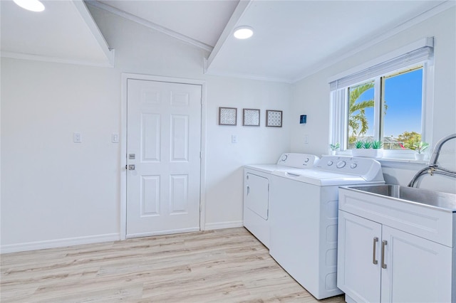 clothes washing area with washer and clothes dryer, light wood-type flooring, cabinets, crown molding, and sink