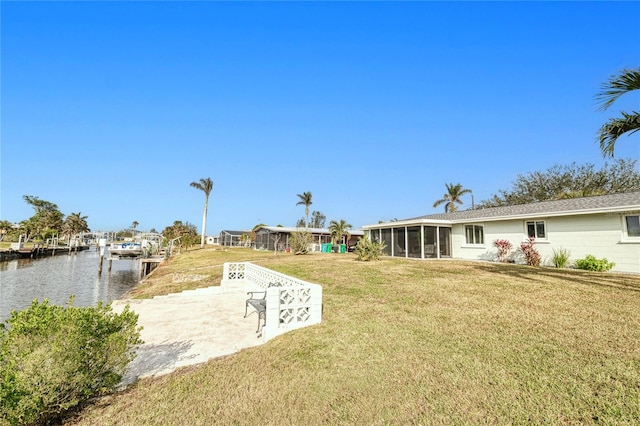 view of yard with a sunroom, a dock, and a water view