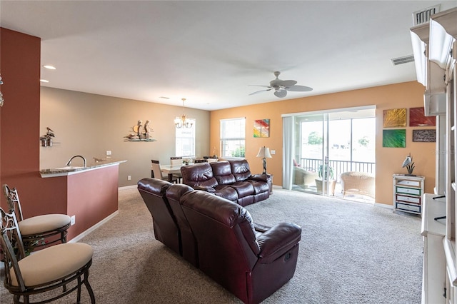 living room featuring ceiling fan with notable chandelier and light carpet