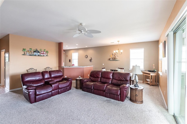 carpeted living room featuring a wealth of natural light and ceiling fan with notable chandelier