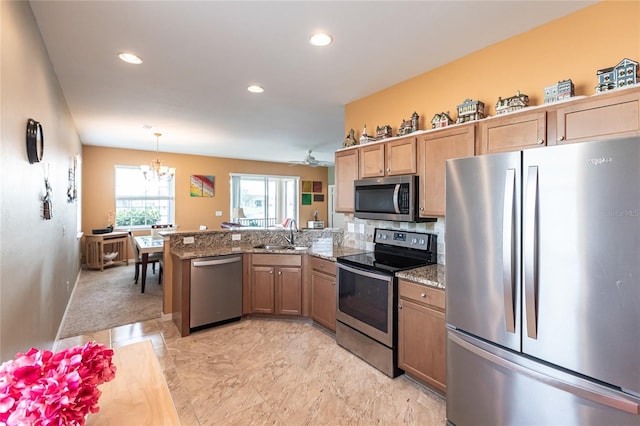 kitchen with stone counters, kitchen peninsula, sink, hanging light fixtures, and stainless steel appliances