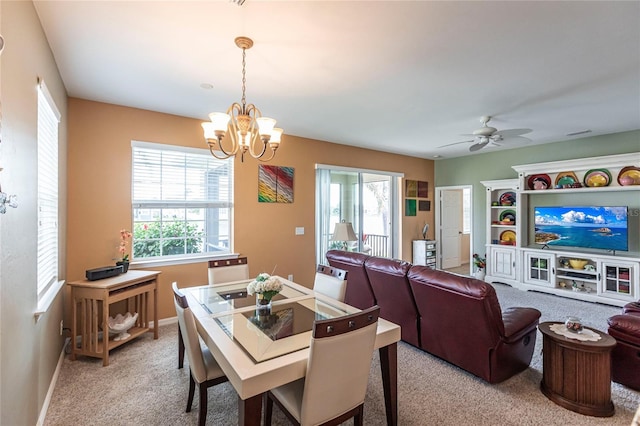 dining space with light colored carpet, ceiling fan with notable chandelier, and a healthy amount of sunlight