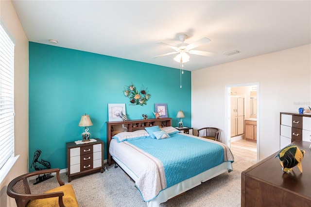 bedroom with ceiling fan, connected bathroom, and light carpet