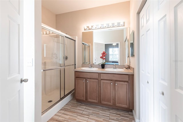 bathroom featuring a shower with shower door and vanity