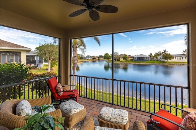 sunroom with ceiling fan and a water view