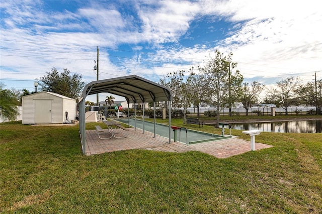 view of property's community with a lawn, a water view, and a storage unit