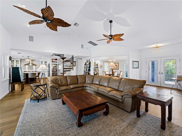 living room featuring light hardwood / wood-style floors, high vaulted ceiling, french doors, and ceiling fan with notable chandelier