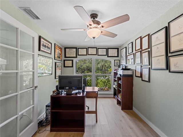 office space featuring a textured ceiling, ceiling fan, and light hardwood / wood-style flooring