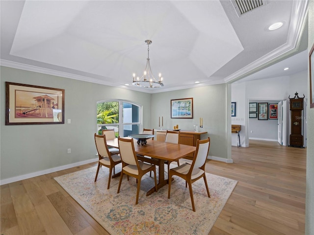 dining area with a raised ceiling, a notable chandelier, and crown molding