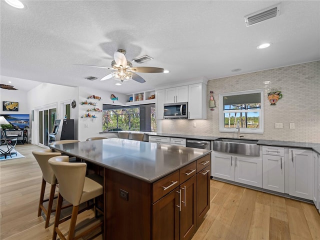 kitchen with a breakfast bar area, stainless steel appliances, white cabinetry, and a kitchen island