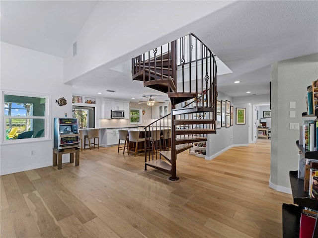 staircase with ceiling fan and wood-type flooring