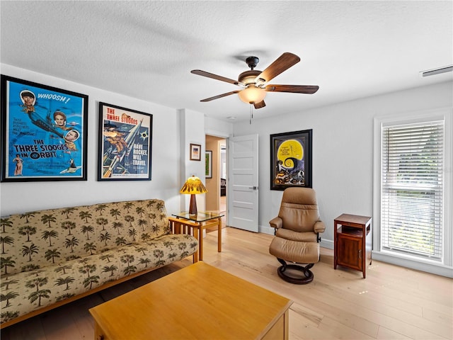 living room featuring a textured ceiling, ceiling fan, and hardwood / wood-style flooring