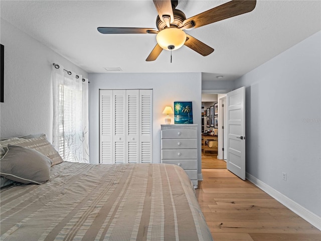 bedroom with ceiling fan, light hardwood / wood-style floors, and a closet