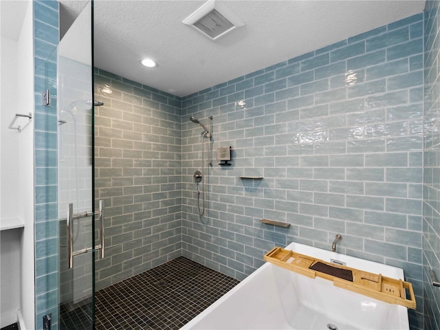 bathroom featuring tile walls, independent shower and bath, and a textured ceiling