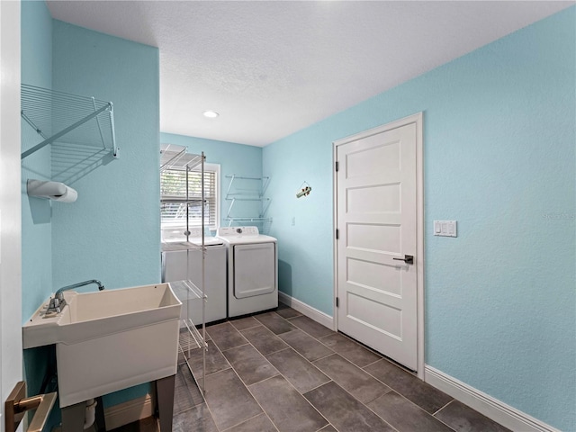 clothes washing area featuring a textured ceiling, independent washer and dryer, and sink