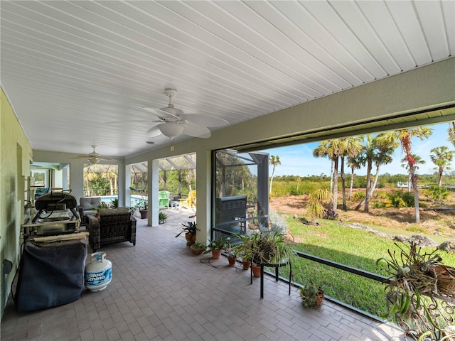 view of patio / terrace featuring ceiling fan, a pool, and glass enclosure