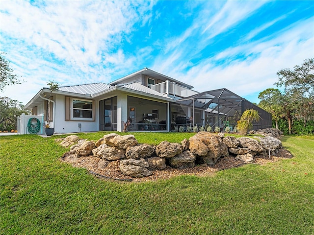 rear view of house with a balcony, a lanai, and a lawn