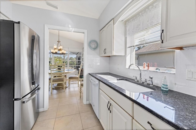 kitchen with sink, vaulted ceiling, stainless steel refrigerator, and white cabinetry