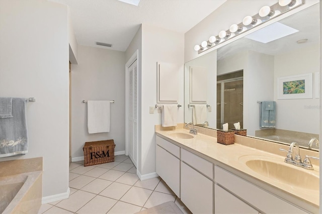 bathroom featuring vanity, a skylight, tile patterned floors, and plus walk in shower