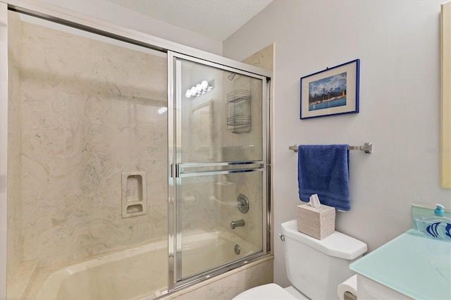 full bathroom with combined bath / shower with glass door, vanity, toilet, and a textured ceiling