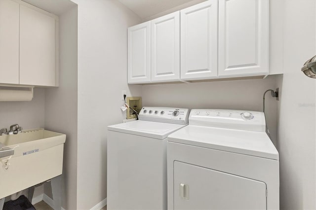 clothes washing area featuring sink, washer and dryer, and cabinets