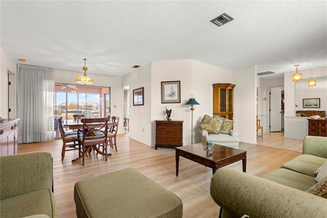 living room featuring a notable chandelier, a textured ceiling, and light hardwood / wood-style flooring