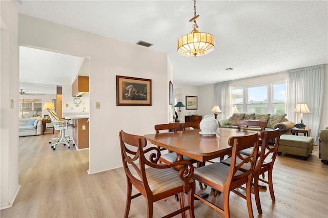 dining room with ceiling fan, a textured ceiling, and light wood-type flooring