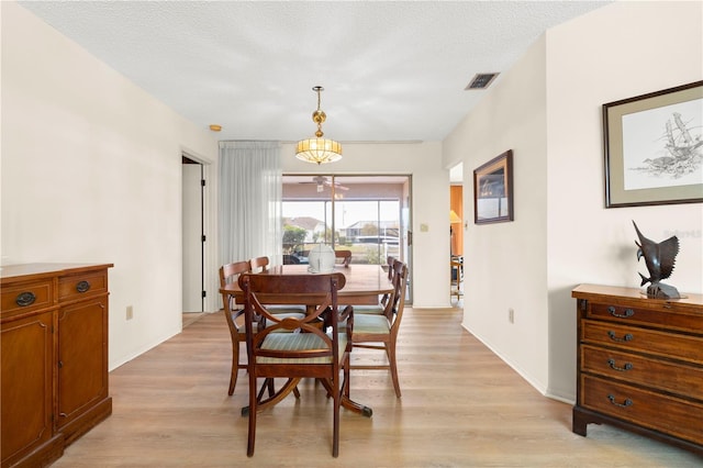 dining room featuring light wood-type flooring and a textured ceiling