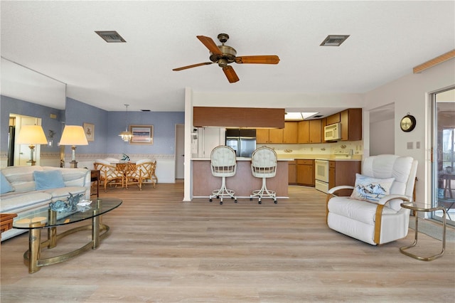 living room featuring light hardwood / wood-style floors, a textured ceiling, and ceiling fan