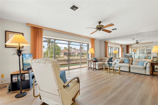 living room featuring light hardwood / wood-style floors, a textured ceiling, and ceiling fan