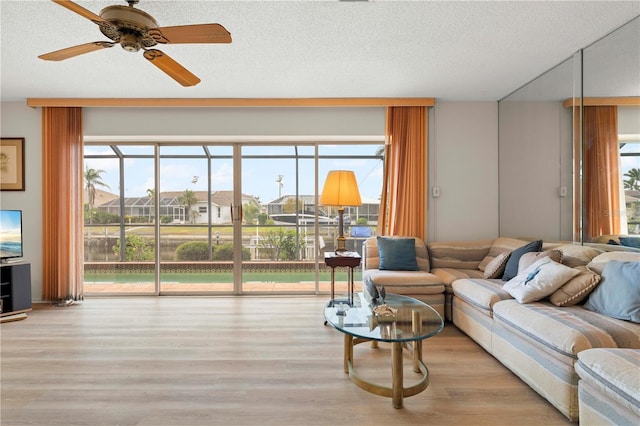 living room with ceiling fan, a textured ceiling, and light hardwood / wood-style floors