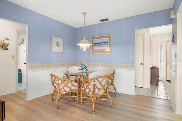 dining area with a textured ceiling and light hardwood / wood-style flooring