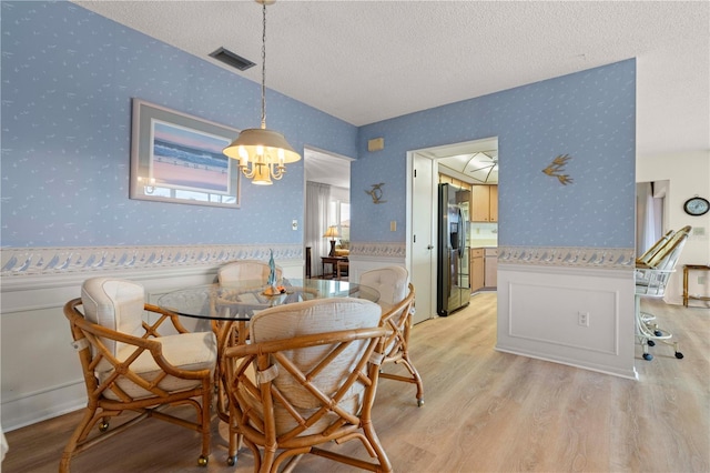 dining room featuring a textured ceiling and light wood-type flooring