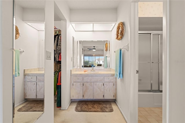 bathroom featuring ceiling fan, enclosed tub / shower combo, and vanity