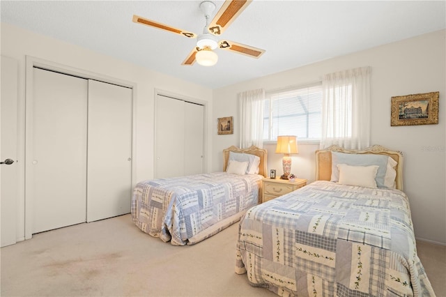 carpeted bedroom with ceiling fan and two closets