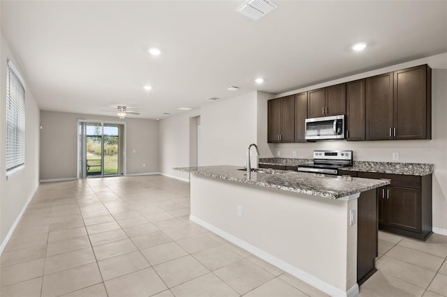 kitchen with ceiling fan, a center island with sink, sink, light tile patterned flooring, and appliances with stainless steel finishes