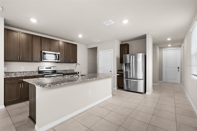 kitchen featuring sink, light tile patterned flooring, dark brown cabinetry, a kitchen island with sink, and stainless steel appliances