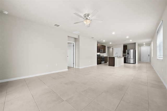 unfurnished living room featuring ceiling fan, light tile patterned floors, and sink