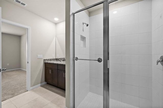 bathroom with a shower with door, tile patterned floors, and vanity