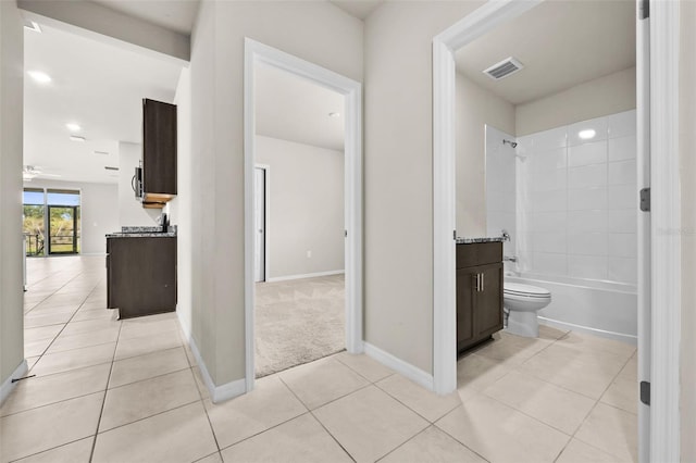 full bathroom with tiled shower / bath, tile patterned flooring, vanity, toilet, and ceiling fan