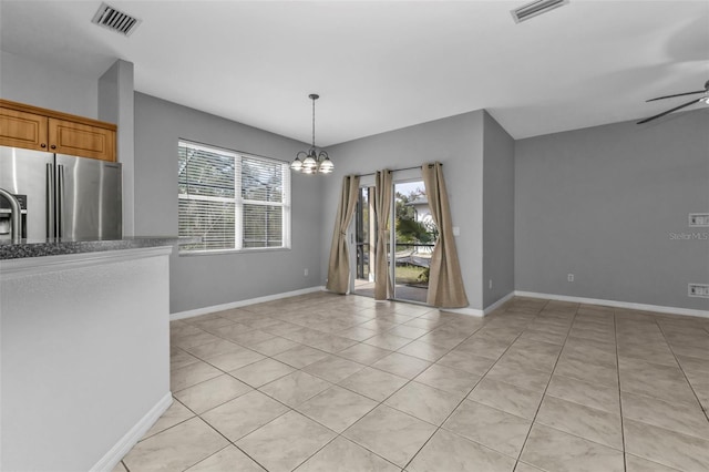 unfurnished dining area with light tile patterned floors, ceiling fan with notable chandelier, and a healthy amount of sunlight