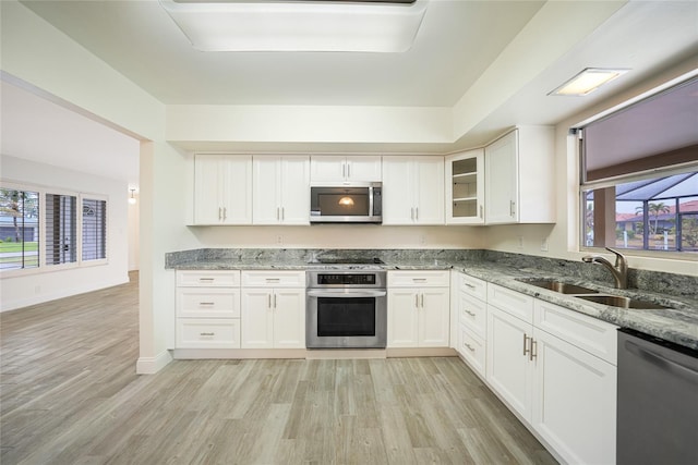 kitchen featuring white cabinetry, sink, stone counters, and appliances with stainless steel finishes