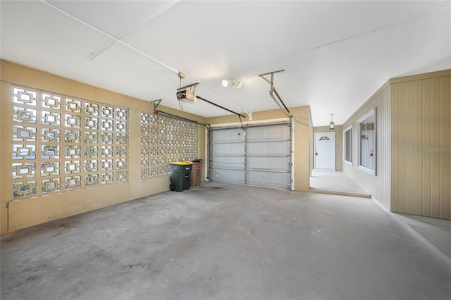 garage featuring a garage door opener and wooden walls