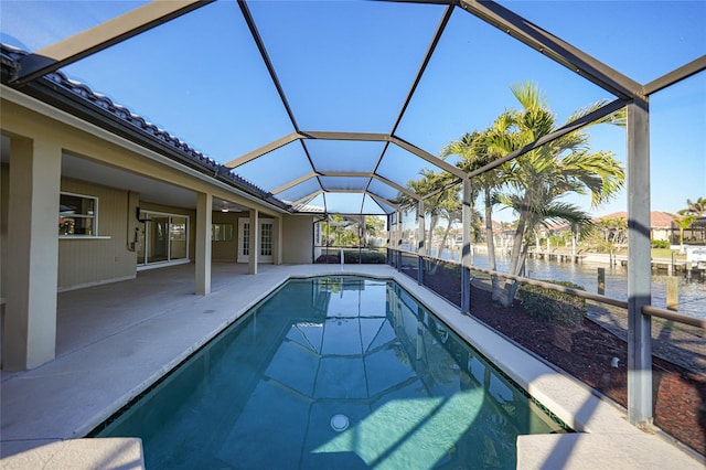 view of pool with a patio area, glass enclosure, and a water view