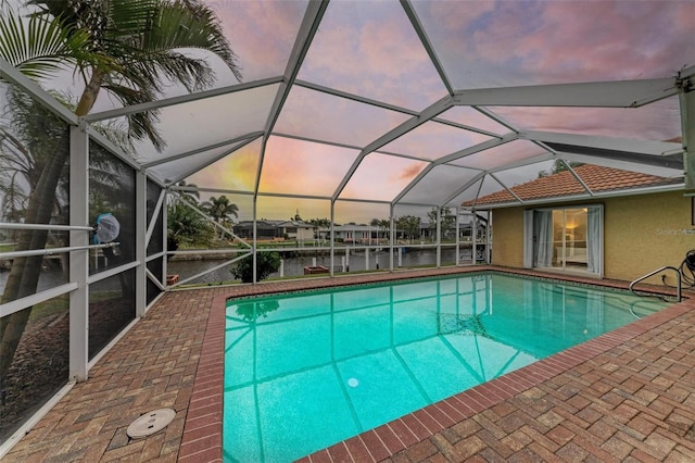 pool at dusk with a water view and a lanai